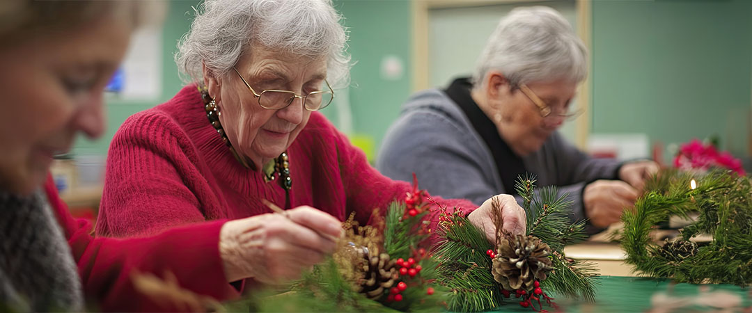Seniors working on a wreath craft and wearing festive clothing